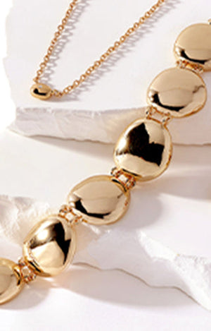Model is wearing gold necklace